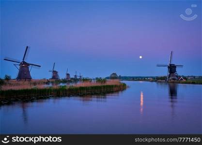 Netherlands rural lanscape with windmills at famous tourist site Kinderdijk in Holland in twilight with full moon. Windmills at Kinderdijk in Holland. Netherlands
