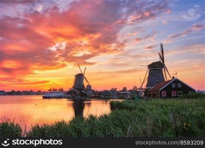 Netherlands rural scene - - windmills at famous tourist site Zaanse Schans in Holland on sunset with dramatic sky. Zaandam, Netherlands. Windmills at Zaanse Schans in Holland on sunset. Zaandam, Nether