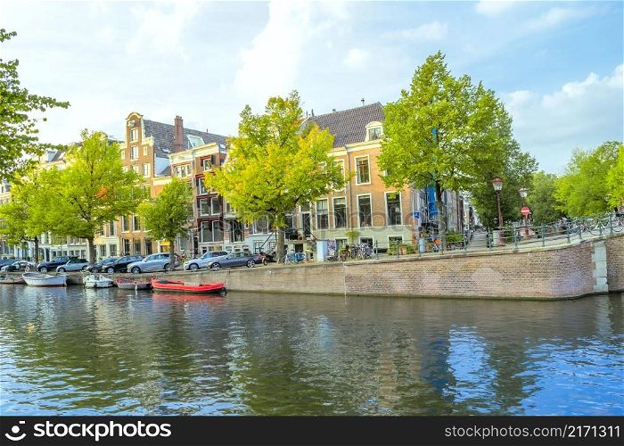 Netherlands. Spring day on the Amsterdam Canal. Boats moored on the water and cars on the embankment. Spring on the Amsterdam Canal