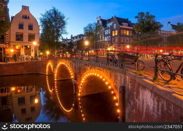Netherlands. Stone bridge with three arches on the Amsterdam Canal. Lots of parked bikes. End of the night. End of the Night on the Amsterdam Bridge