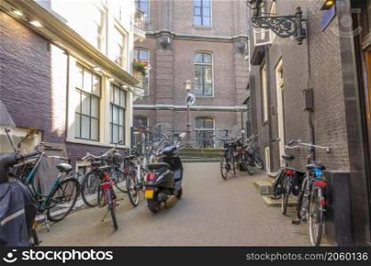 Netherlands. Sunny day in Amsterdam. Small Side Street With Bicycles and Scooters. Small Side Street of Amsterdam With Bicycles and Scooters
