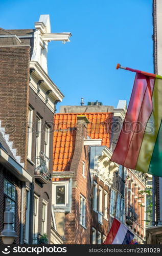 Netherlands. Sunny day in Amsterdam. Typical house roofs and LGBT flag. Amsterdam Rooftops and LGBT Flag