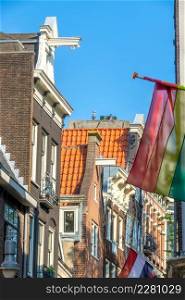 Netherlands. Sunny day in Amsterdam. Typical house roofs and LGBT flag. Amsterdam Rooftops and LGBT Flag