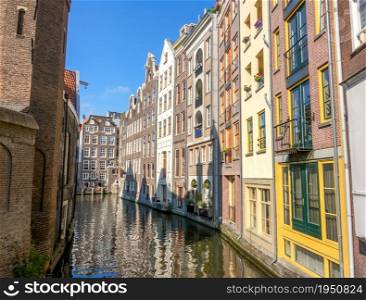 Netherlands. Sunny day on the Amsterdam canal. Traditional Dutch houses by the water. Amsterdam Canal Houses on a Sunny Day