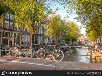 Netherlands. Sunny spring day in Amsterdam. Bicycles parked on a canal bridge with a Dutch sign