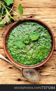 Nettle cream soup on wooden background.Soup with fresh nettles. Russian traditional nettle soup