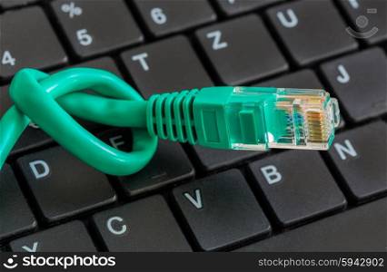Network cable with green knot and keyboard. Network cable with green knot and keyboard.