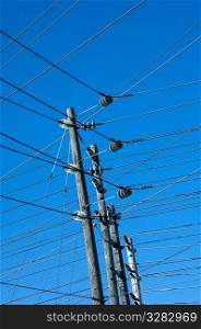 Network of power lines against a blue sky.