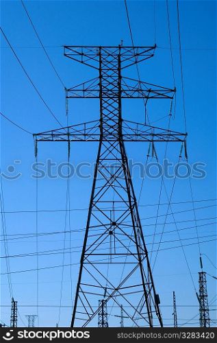 Network of power lines on hydro tower against a blue sky.