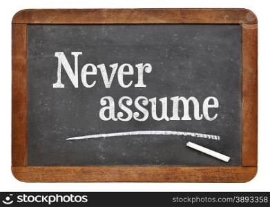 Never assume advice - text in white chalk on a vintage slate blackboard