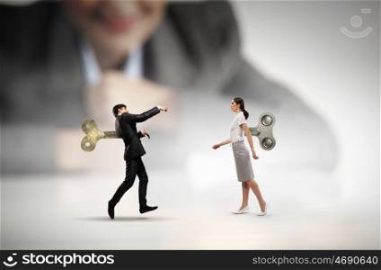 Never endless energy. Young businessman and businesswoman walking with wind up key in his back
