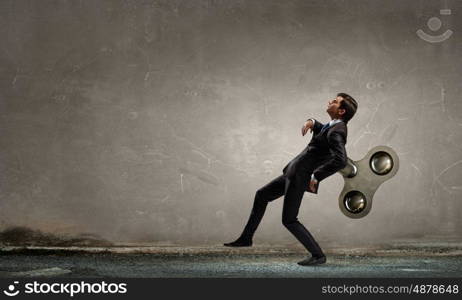 Never endless energy. Young businessman walking with wind up key in his back