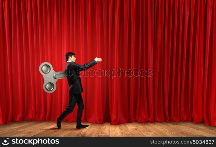 Never endless energy. Young businessman walking with wind up key in his back