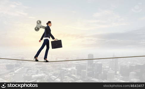 Never endless energy. Young businesswoman walking with wind up key in his back