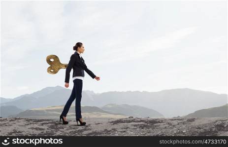 Never endless energy. Young businesswoman walking with wind up key in his back