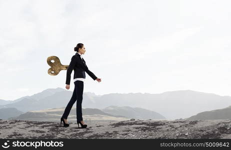 Never endless energy. Young businesswoman walking with wind up key in his back