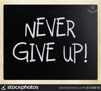 ""Never give up" handwritten with white chalk on a blackboard"