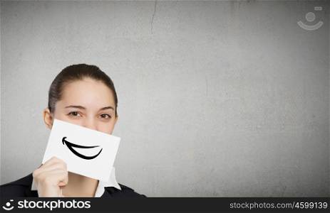 Never stop smiling. Pretty young girl holding white card with drawn smile
