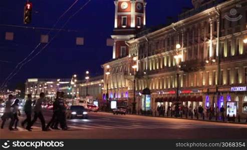 Nevsky Prospect at night: people crossing the road near illuminated old building. St. Petersburg, Russia.
