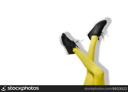 New Black female sneakers on long slender woman legs in yellow tights isolated on white background.. New Black female sneakers on long slender woman legs in yellow tights isolated on white background