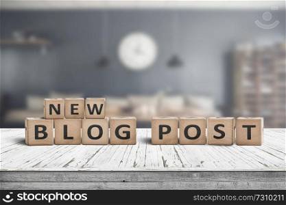 New blog post sign on a wooden desk with a stylish living room on a blurry background