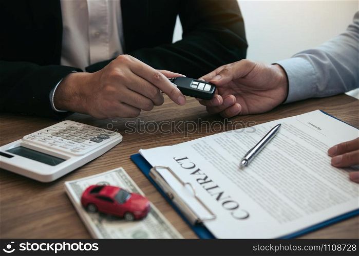 New car buyers enter the car keys and sign the contract documents in the showroom of the car salesman&rsquo;s office.