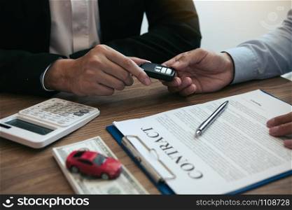 New car buyers enter the car keys and sign the contract documents in the showroom of the car salesman&rsquo;s office.
