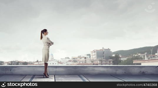 New day for business. Young elegant businesswoman on roof looking at city