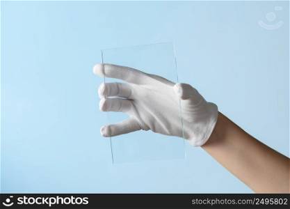 New features of glass or plastic research, hand in glove holding rectangular piece of transparent material