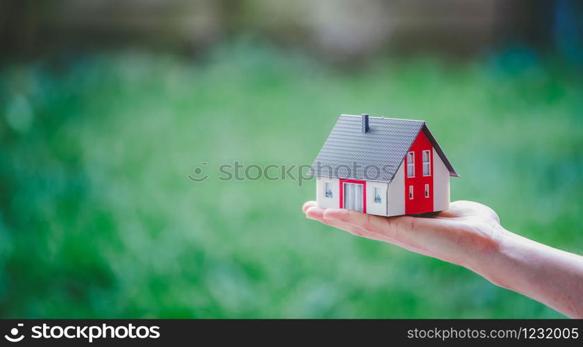 New home and house concept: Red house model outdoors in male hand, copy space