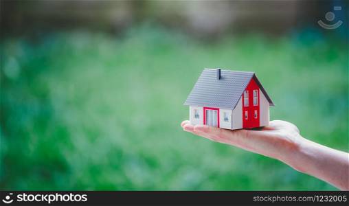 New home and house concept: Red house model outdoors in male hand, copy space