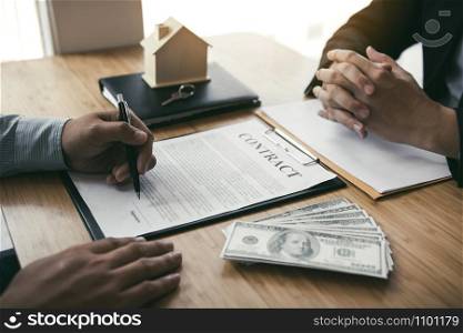 New home buyers are signing a home purchase contract at the agent&rsquo;s desk.
