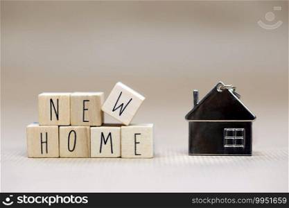 New Home text written with wooden cubes background with symbol of cozy little house with blurred background design, purchase real estate,mortgage loan, property owner concept background close up. New Home text written with wooden cubes background with symbol of cozy little house with blurred background design, purchase real estate,mortgage loan, property owner concept background