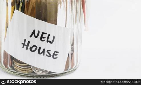 new house label glass jar with coins against white background