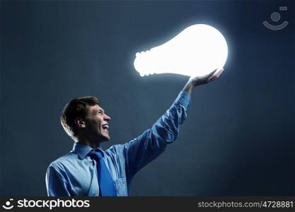 New idea. Businessman holding huge electrical bulb in hand