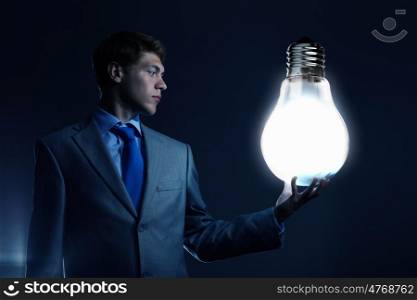 New idea. Businessman holding huge electrical bulb in hand