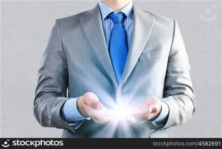 New idea. Close up of businessman holding ray of light in palms
