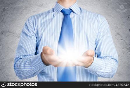New idea. Close up of businessman holding ray of light in palms