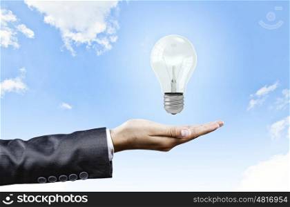 New idea. Close up of businesswoman hand with bulb in palm