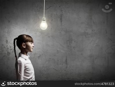 New idea. Cute girl of school age and electrical bulb above head