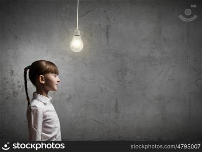 New idea. Cute girl of school age and electrical bulb above head