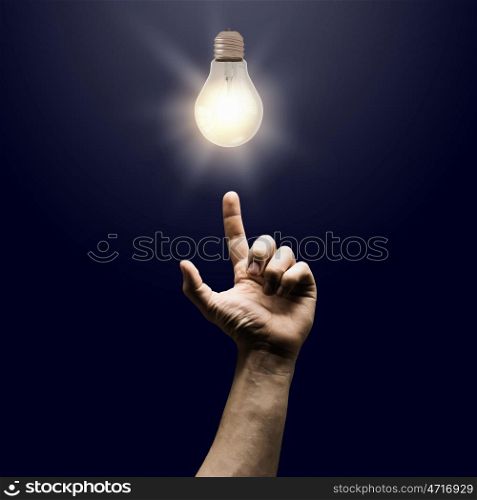 New idea. Human hand pointing with finger at electrical bulb