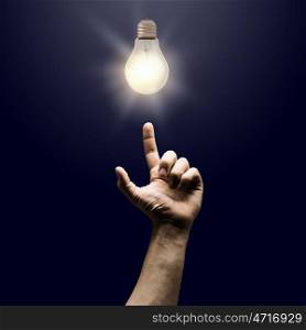 New idea. Human hand pointing with finger at electrical bulb