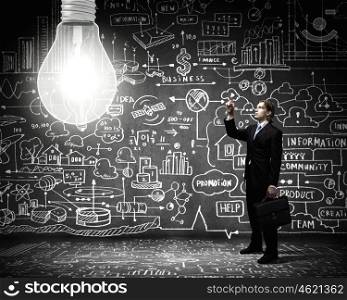 New idea. Young businessman and big light bulb against sketch background