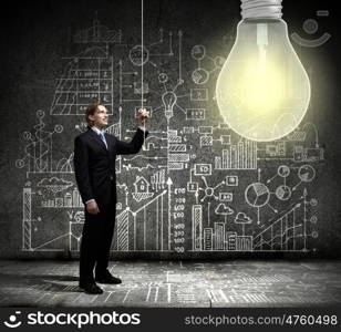 New idea. Young businessman and big light bulb against sketch background