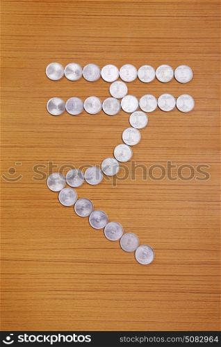 New Indian rupee currency symbol created by arranging coins over wooden background