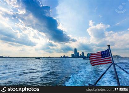 New Jerysey city skyline from boat with American flag in New York US