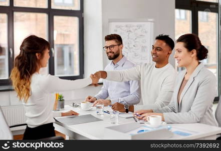 new job, hiring and employment concept - international team of recruiters having interview and shaking hands with asian female employee at office. recruiters having job interview with employee