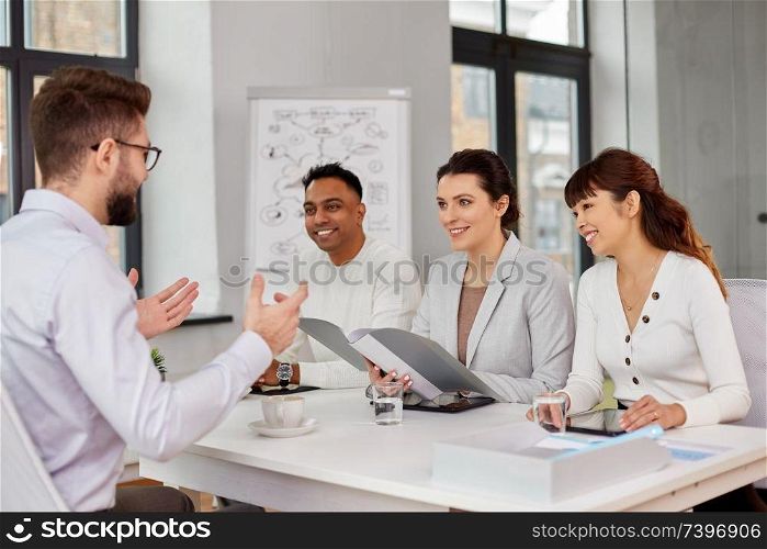 new job, hiring and employment concept - international team of recruiters having interview with male employee at office. recruiters having job interview with male employee