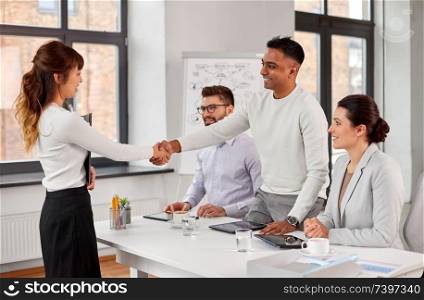 new job, hiring and employment concept - international team of recruiters having interview and shaking hands with asian female employee at office. recruiters having job interview with employee